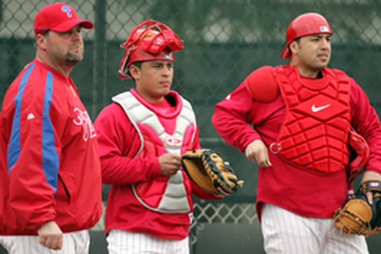 Phillies catching instructor Mike Billmeyer (left) shares a word with Carlos Ruiz (center) and Rod Barajas, the latter of whom turned down a more lucrative offer from the Blue Jays.