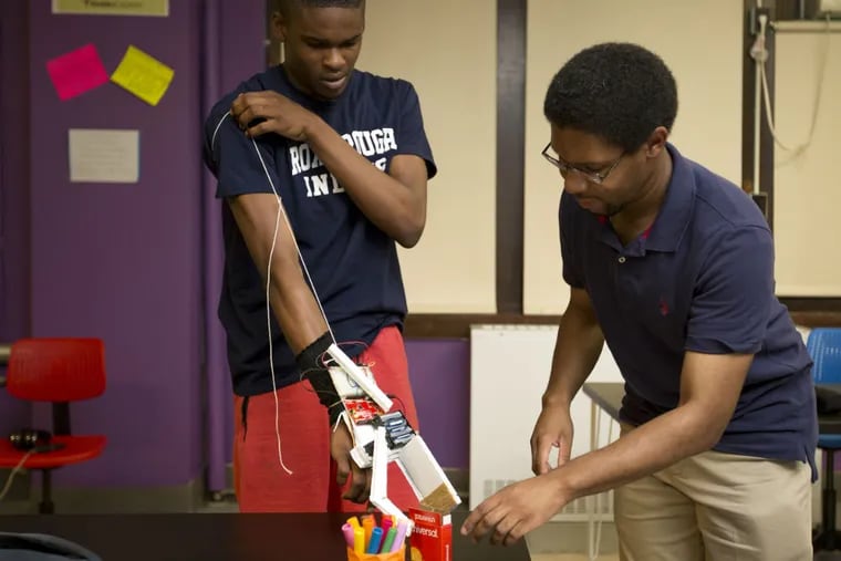 Andrew Bennett-Jackson, a graduate student at Drexel who works for Drexel's ExCITe Center, helps Roxborough High School graduate, Darr Freeman, work with a prosthetic arm designed by students Thursday, June 22, 2017. Roxborough High School created a STEAM lab through collaboration with Drexel and a 5-year $1 million grant.