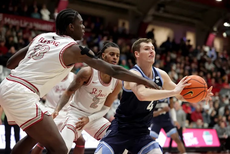 Villanova's Chris Arcidiacono (right) passes after driving the lane against Rasheer Fleming (left) and Erik Reynolds II (center) of St. Joseph's during the second half of their game last season at Hagan Arena.