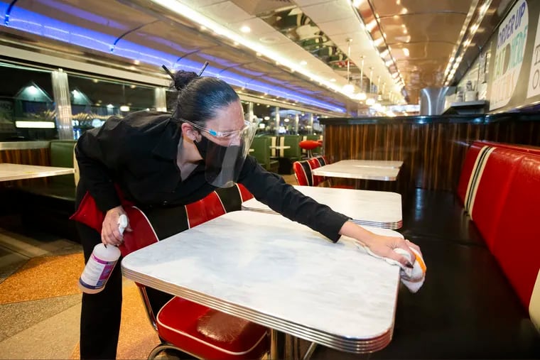 Waitress Elisabeth Benson sanitizes tables at the Mayfair Diner in 2020.