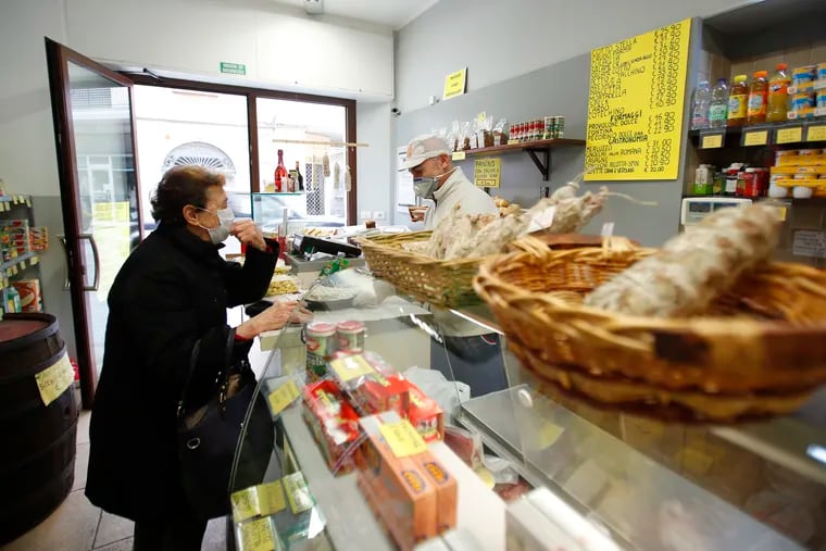An elderly woman buys food in a deli meat and cold cuts shop in Codogno, Italy, in March.