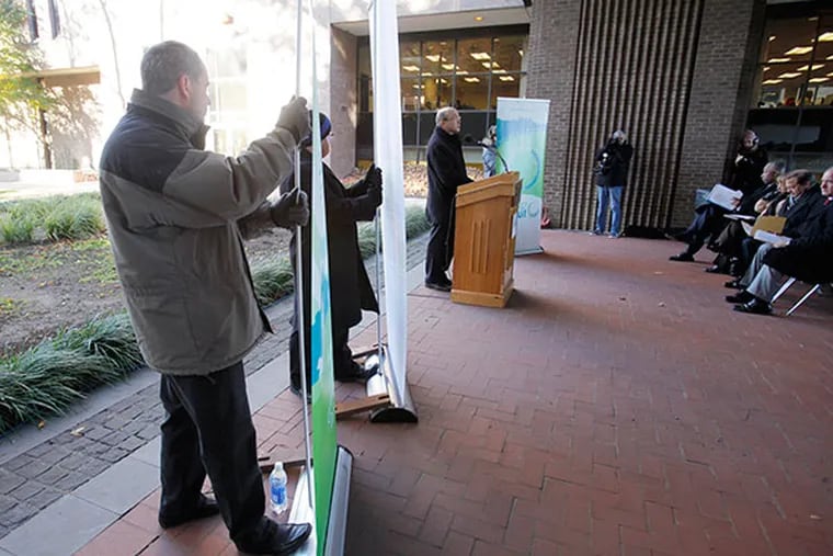Barry Seymour, Executive Director of the Delaware Valley Regional Planning Commission, speaks (far right), as John Boyle (left), of the Bicycle Coalition of Greater Philadelphia, and Shawn Megill Legendre (middle), of the Delaware Valley Regional Planning Commission hold onto signs at Rutgers in Camden on November 13, 2013. Regional planners announced $4 million for bike and pedestrian trails across the region, including $400,000 for the planned new walkway on the Camden side of the Ben Franklin Bridge. ( ELIZABETH ROBERTSON / Staff Photographer )