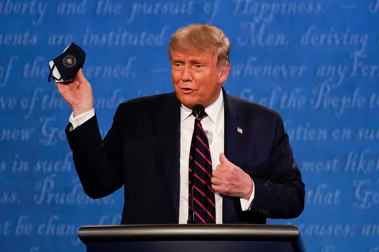In this Sept. 29, 2020, file photo, President Donald Trump holds up his face mask during the first presidential debate at Case Western University and Cleveland Clinic, in Cleveland. President Trump and first lady Melania Trump have tested positive for the coronavirus, the president tweeted early Friday.