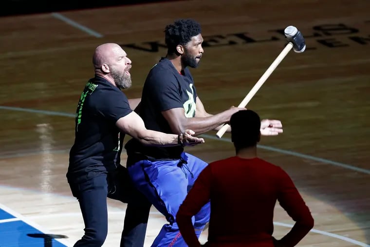 Sixers center Joel Embiid holds a sledgehammer with WWE wrestler Triple H during pregame ceremonies before the Sixers played the Atlanta Hawks in Game 1 of the NBA Eastern Conference playoff semifinals on Sunday.