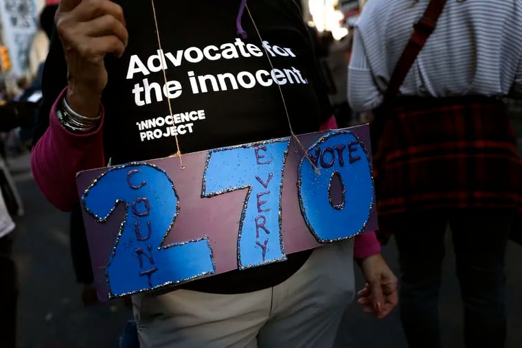 A person holds a sign referring to the number of electoral votes needed to win the presidency while demonstrating outside the Pennsylvania Convention Center where votes are being counted, Thursday, Nov. 5, 2020, in Philadelphia, following Tuesday's election.