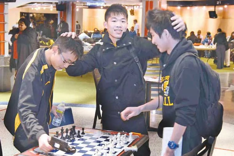 Senior Jiansheng Guo (cq-center) congratulates his Engineering and Science HS chess teammates after they won the first place high school city chess championship at the Philadelphia Scholastic Chess League City Championships at Citizens Bank Park's Diamond Club,March 6, 2013. At left is junior Kent Huang (cq) and at right is senior Xuhui Huang (cq-no relation) who had just ending his match, sealing the victory. ( TOM GRALISH / Staff Photographer )