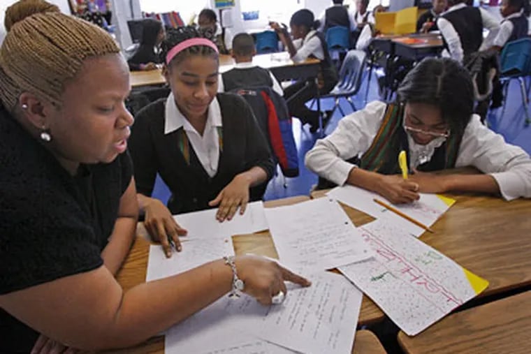 Kwame Williams, a mentor teacher at the Imani Education Circle Charter School in the Germantown section of Philadelphia, works with students Deja Bagby, 12, and LaTaya Elder, 12, on Tuesday. (Alejandro A. Alvarez / Staff Photographer)