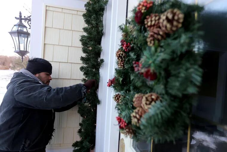 Antelmo Gonzales, of Michigan Holiday Lighting, puts the finishing touches on holiday decorations on a 3,500 square foot home in Clarkston, Mich., Dec. 11, 2013. (Andre J. Jackson/Detroit Free Press/MCT)