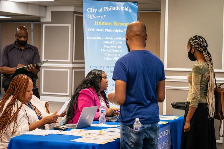Lisa Pace, senior human resources analyst for the City of Philadelphia, (seated center), talks with applicants at a job fair that took place on Aug. 21, 2023.