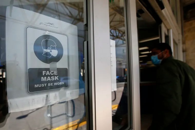 A sign asking riders to wear a face mask hangs at the front entrance to the Philadelphia Greyhound Terminal.
