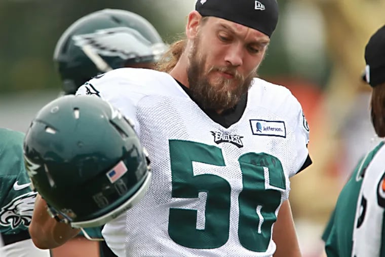Eagles linebacker, #56,  Bryan Braman, center, shakes the
dirt and grass out of his helmet before practice begins on Friday
during training camp. (Michael Bryant/Staff Photographer )