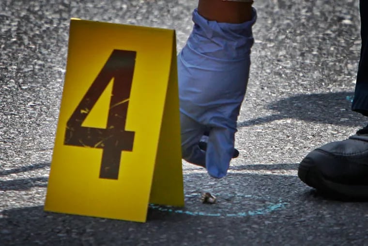 A Crime Scene Unit officer collects ballistic evidence at a shooting scene in 2012.