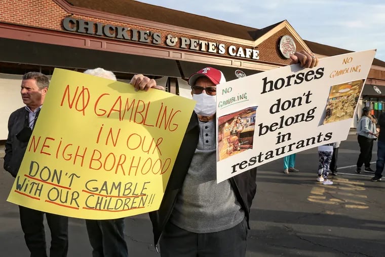 Not wanting to be identified an anti gambling protester holds signs outside Chickie's & Pete's on Packer avenue. Neighbors don't want a Turf Club off-track betting parlor set up inside the restaurant.  Monday, April 5, 2021