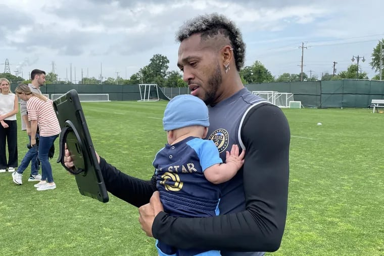 Union midfielder Jose Andres Martinez holds his newborn baby Jack while watching a video with messages congratulating him for being named an All-Star.