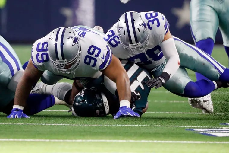 Cowboys lineman Antwaun Woods (99) flattens Eagles running back Corey Clement as safety Jeff Heath flies in for support in the their 29-23 overtime win in Dallas last December.