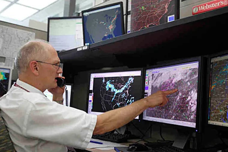 With monitors at the Storm Prediction Center indicating trouble, lead forecaster David Imy talks with local weather centers about issuing a tornado watch. (Sara Phipps/For the Inquirer)