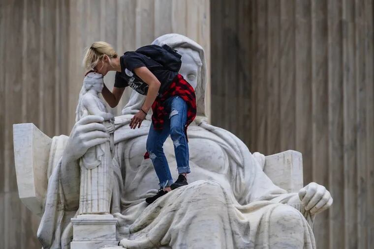 Jessica Campbell-Swanson, an activist from Denver, kisses the sculpture known as the Statue of Contemplation of Justice on the steps of the Supreme Court Building where she and others protested the confirmation of Brett Kavanaugh as the high court's newest justice, in Washington, Saturday, Oct. 6, 2018.