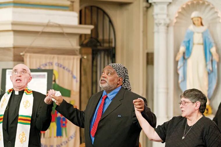 At St. Vincent De Paul Church in Germantown on Wednesday, pastor Sylvester Peterka (left), exonerated death-row inmate Harold Wilson (center), and other participants in a prayer rally against capital punishment join hands and sing after the announcement of the stay of execution for inmate Richard Glossip in Oklahoma. (CHARLES FOX/Staff Photographer)