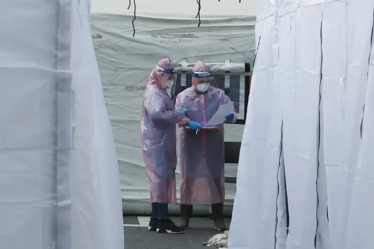 Medical staff wearing protective suits check documents as they wait for people with suspected symptoms of the new coronavirus at a testing facility in Seoul, South Korea, Wednesday, March 4, 2020. The coronavirus epidemic shifted increasingly westward toward the Middle East, Europe, and the United States on Tuesday, with governments taking emergency steps to ease shortages of masks and other supplies for front-line doctors and nurses.