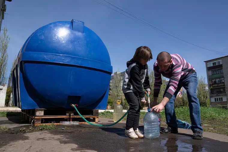 A girl helping a man fill cans with water from a tank installed for residents of Toretsk, eastern Ukraine, on Monday.