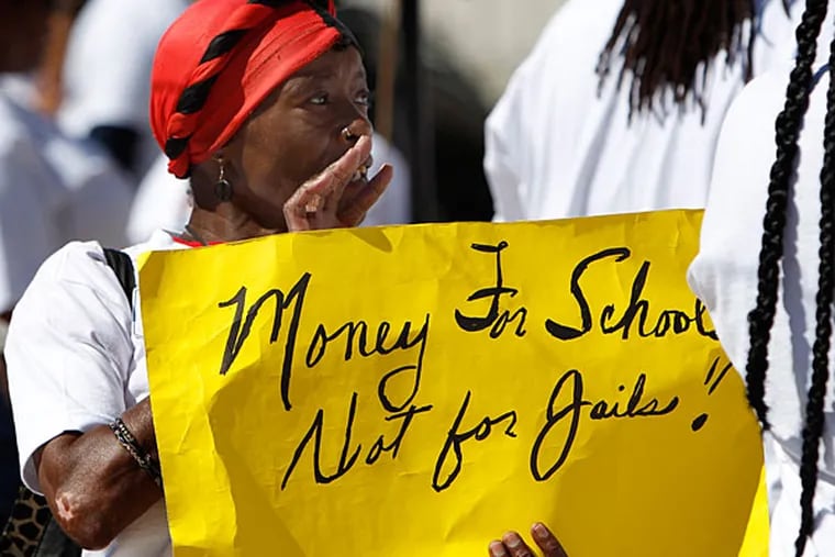 Hazel McGirt, a school district employee, holds up a sign during a protest in front of the School District of Philadelphia headquarters in Philadelphia on August 14, 2013. A group of parents, students, and clergy lined the steps in front of the school district headquarters for a one-day resumption of fasting to bring attention to the 1,202 laid-off student safety staff. ( DAVID MAIALETTI / Staff Photographer )