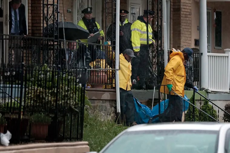 Police remove the body of a shooting victim from the porch of a home in the 5900 block of Palmetto Street in Lawncrest on April 28.