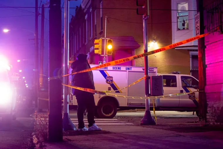 A bystander watches police investigate and clean up after a shooting in North Philadelphia on 10th Street near French left three people dead Saturday, Dec. 22, 2018. MARGO REED / Staff Photographer
