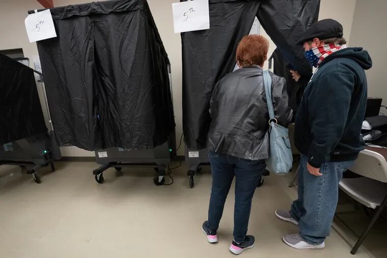 Danny D'Agostino (right) machine inspector, assists a voter at the polling place at Barry Playground in South Philadelphia on Election Day last year.