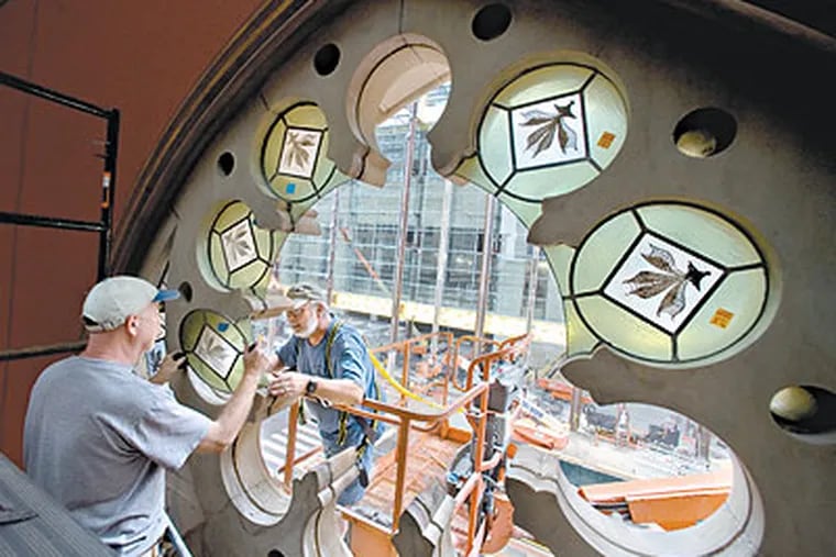 Rick Prigg (left), 55, and Jenkyn Powell, 59, both from Willet Hause Architectural Glass Studio insert a section of The Rose Window at the Pennsylvania Academy of Fine Arts after the first complete and total restoration of the window since it was originally installed in 1876. (Clem Murray / Staff Photographer)