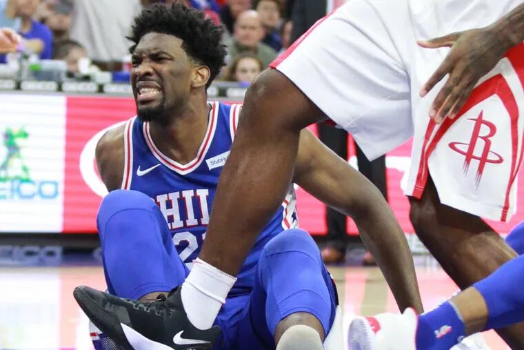Joel Embiid of the Sixers grimaces after landing hard against the Houston Rockets during the first half of a game at the Wells Fargo Center on Oct. 25, 2017. CHARLES FOX / Staff Photographer