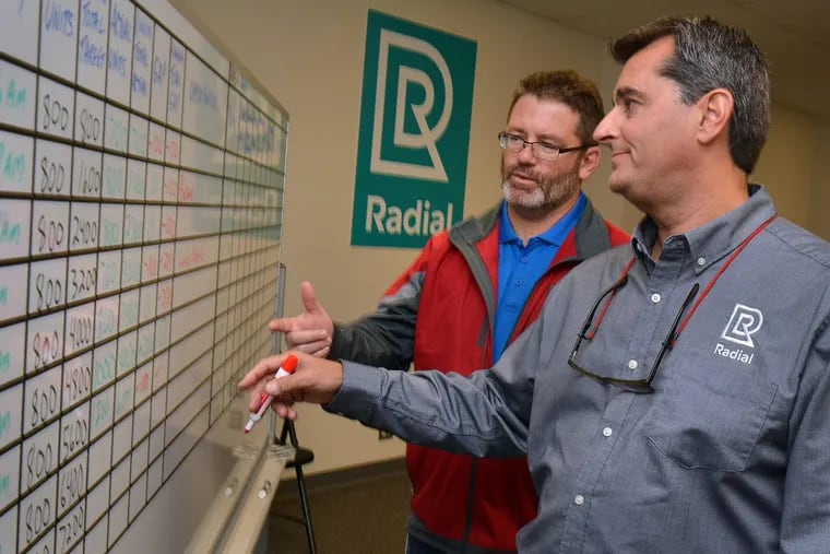 Radial HR manager Patrick Koreck (left) and  director of fulfillment operations Alex Economos go over a daily productivity board at their new fulfillment center (warehouse) in Burlington City.