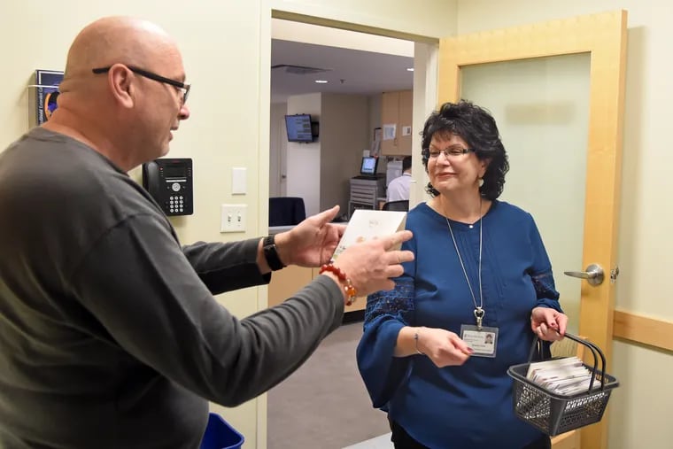 Penn employee Sharon Civa (right) gives a card to Wendell Gainer (left) while she visits with his mother, chemotherapy patient Dolly Gainer (not shown) in her room at HUP Feb. 26, 2020. Civa had ovarian cancer, and - while undergoing treatment - started receiving get-well cards from strangers wishing her well. It so lifted her spirits that she vowed that, once she was finished treatment, she'd design her own get-well cards and hand-deliver them to HUP patients.