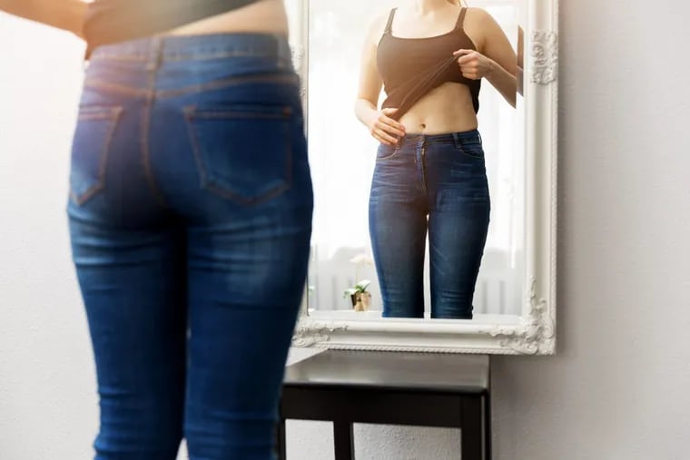 Woman checking her body in front of a mirror.