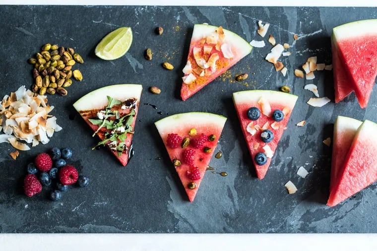Watermelon 'pizza' slices topped with arugula, goat cheese, and balsamic reduction (left), toasted coconut flakes, salt, and curry powder (top), raspberries, pistachios, and honey (center), and blueberries and toasted coconut flakes (right).
