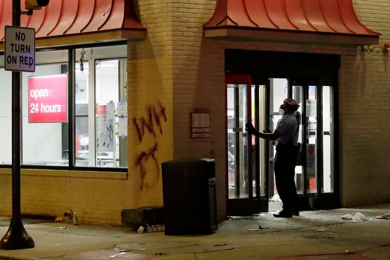 A policeman tries to close the doors to the CVS store at 15th and Spruce St. in the early morning hours of May 31, 2020. The store was looted and ransacked after the George Floyd Philadelphia protest on May 30, 2020, and still temporarily closed as of Tuesday, June 2.