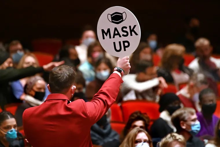 An usher holds up a reminder for the audience to mask up before a Philadelphia Orchestra concert in Verizon Hall in January.