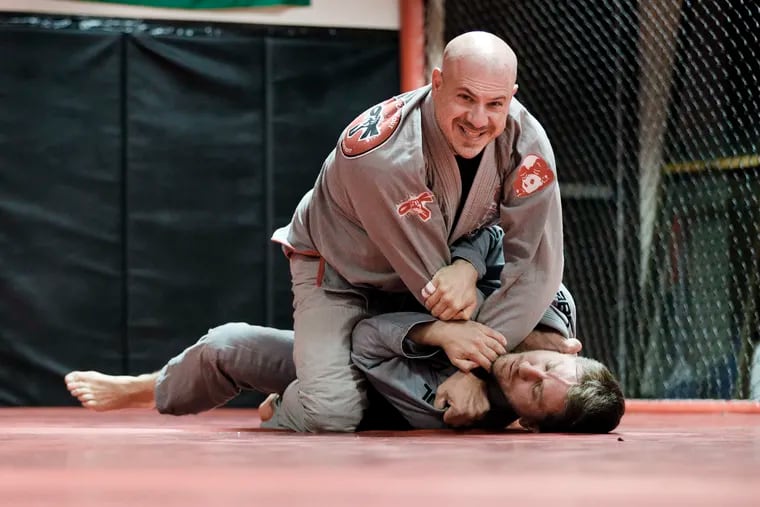 Gregory Cappello (top) smiles as he helps Mark Szymanik of West Deptford warmup for a Brazilian jujitsu class at the Ken Brach martial arts school in Voorhees, N.J., on Oct. 30, 2020.