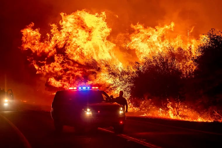 Flames lick above vehicles on Highway 162 as the Bear Fire burns in Oroville, Calif., on Wednesday, Sept. 9, 2020. The blaze, part of the lightning-sparked North Complex, expanded at a critical rate of spread as winds buffeted the region. (AP Photo/Noah Berger)