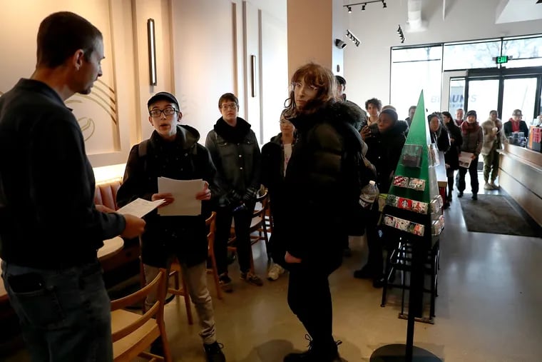 TJ Bussiere, second from left, hands district manager Brian Dragone, far left, an "unfair labor practice" complaint at the Starbucks at Broad and Washington Avenue in Philadelphia on Monday, November 25, 2019. Bussiere and Echo Nowakowska (right), who both work at the Starbucks pictured, led a delegation of Starbucks workers and their supporters to deliver the complaint.