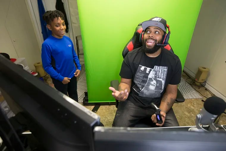 E-sports gamer David Carter of Drexel Hill has about 850,000 followers on YouTube, Facebook, Twitter and Instagram. He does his filming e-sports videos, editing and chatting out of the basement of his Drexel Hill row home.  His son David, 11, left, gives him a hard time as he plays in the basement gaming area on April 25, 2019.