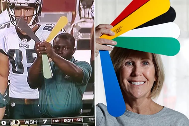 Jill Cakert, inventor of the SignalFan, right, demonstrates how she uses it when coaching softball. The color combinations work with each other to send more than one signal to the players. At left, an Eagles assistant coach holds up SignalFan colors on offense to call plays from the sidelines. (Right: MICHAEL BRYANT/Staff Photographer)