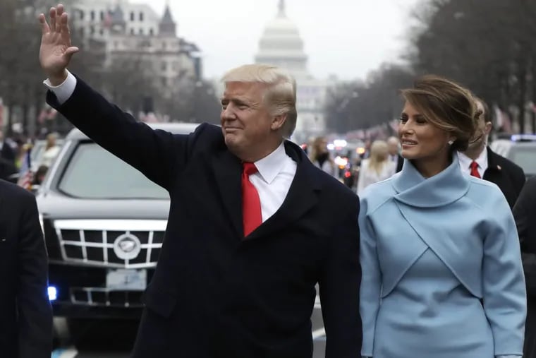 President Donald Trump waves as he walks with First Lady Melania Trump during the inauguration parade on January 20, 2017.