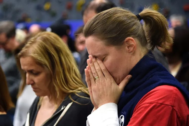 Cherry Hill parent Beth Taubman (right) pauses with others attending the Cherry Hill School Board meeting Feb. 27, during a moment of silence for the victims of the Parkland, Florida school shooting.