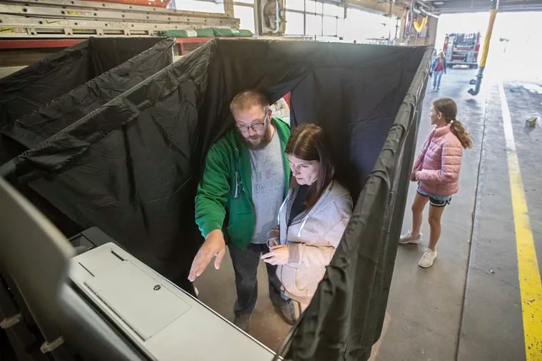Marla Coccia (right) gets instruction from John Chambers, majority inspector for Ward 39, Division 25, on how to use the new voting machines at Engine 49 Firehouse at 13th and Shunk.