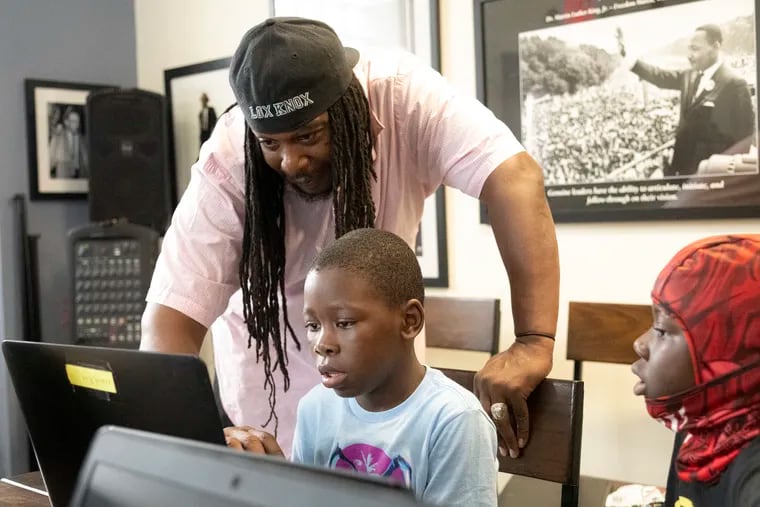 Najee (left) and Naeem Roundtree work with instructor Rasheed Knox during a summer program at the Strawberry Mansion Learning Center, where kids can keep up with reading skills.