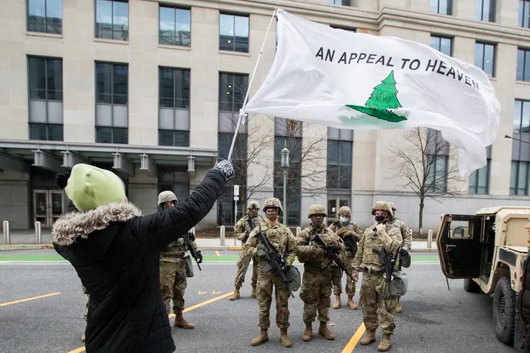 A group of women stop to pray with National Guardsmen by the State Capitol  in Harrisburg in January 2021, displaying the “Appeal to Heaven” flag.