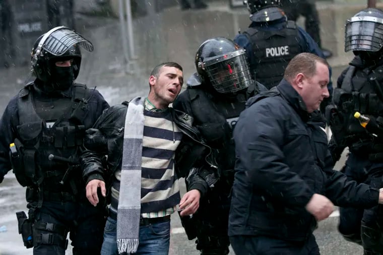 Kosovo police in riot gear detain a supporter of the opposition party during a raidat opposition headquarters in Pristina.
