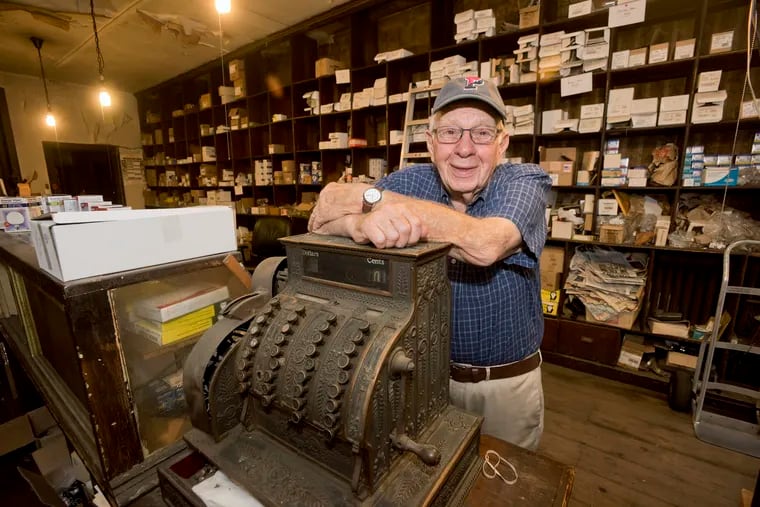 Newton Gold, 88, leans atop the old cash register, circa 1904, in his family shop, Austrian Lamp Company. The business is closing after 100 years of operation on 2nd Street in the Old City section of Philadelphia, September 21, 2018. Avi Steinhardt / For the Inquirer