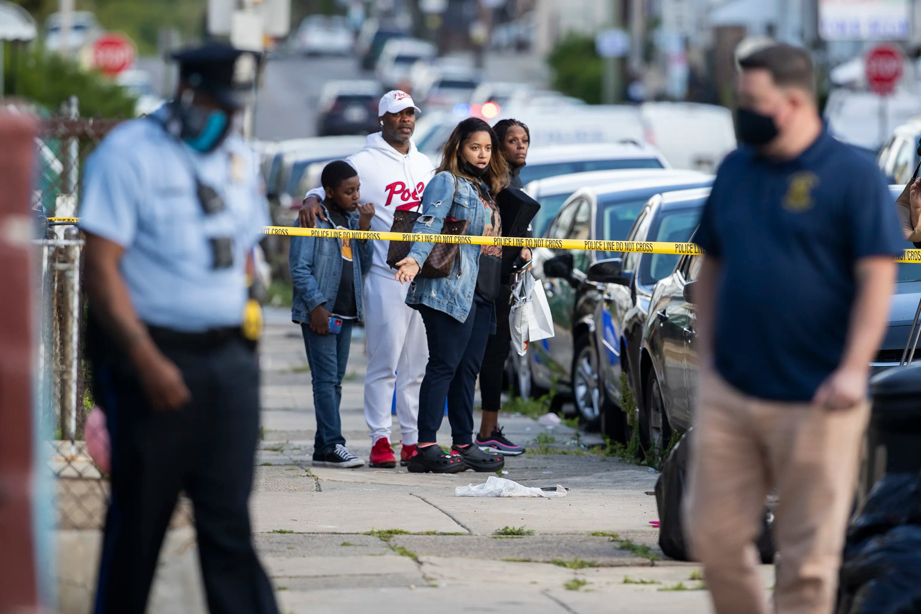 A shooting left one dead and four wounded at South 55th and Kingsessing Avenue on May 12, 2021. Onlookers stop at the scene, which extended south on 55th Street.
