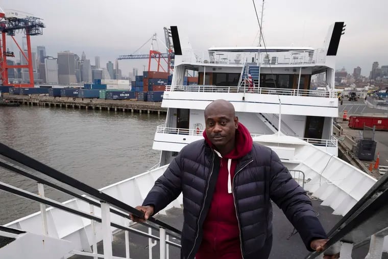 In this Nov. 30, 2018 photo, cruise boat owner Dwayne Braithwaite poses on his boat at a Brooklyn dock in New York. Braithwaite has filed a lawsuit alleging racism and accused the city contractor that runs the docks of punishing him for not paying kickbacks. The city and its contractor, Dock NYC, say Braithwaite and his vessels violated the terms of their docking contracts at least seven times in 77 days - departing late, blasting loud music and blocking commuter ferries by tying up in the wrong spot. Braithwaite will be in a New York City court room on Wednesday, Dec. 19. (AP Photo/Mark Lennihan)